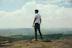 man standing on bolder overlooking the hills and mountains