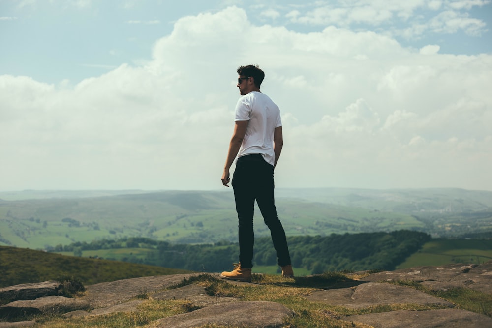 homem de pé em mais ousado com vista para as colinas e montanhas