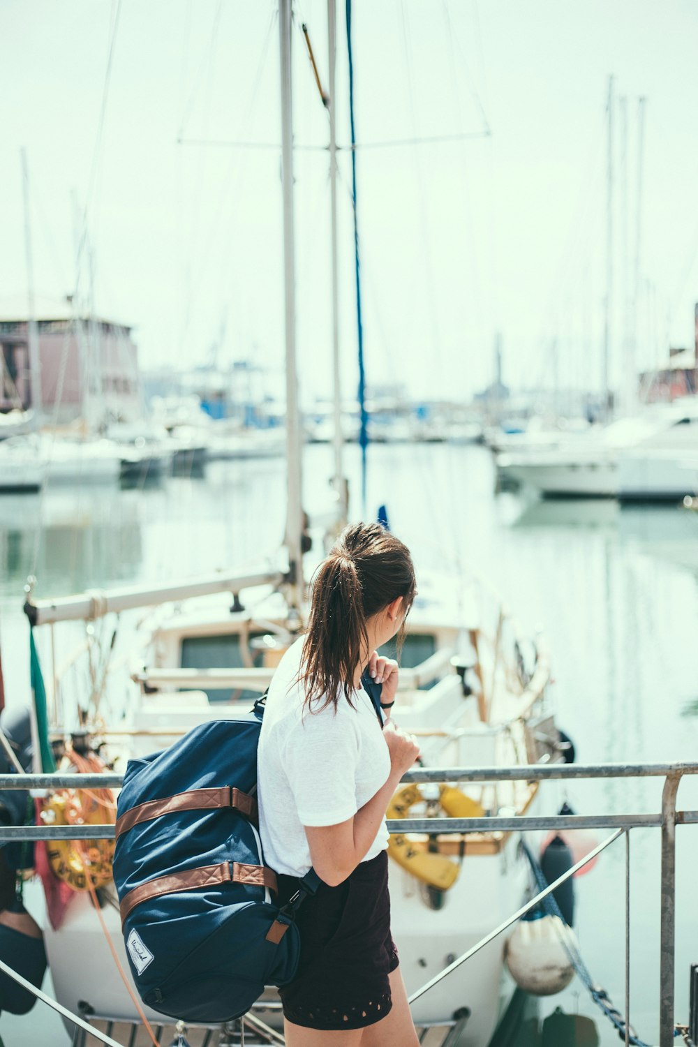 woman wearing white shirt holding blue duffel bag