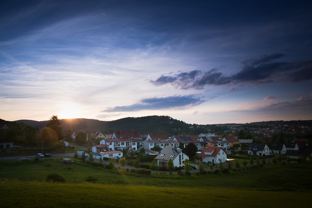 Häuser auf grünem Grasfeld unter bewölktem Himmel während des Tages