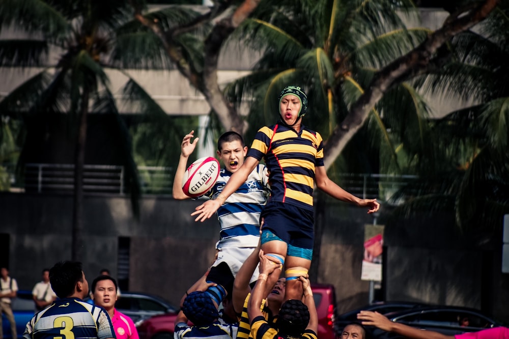 Two men in polo shirts jumping for the ball during a game of rugby.