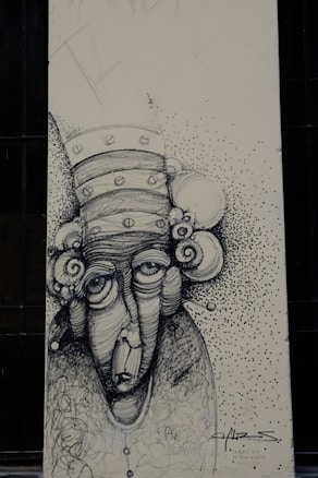 A monochromatic drawing of an abstract face with exaggerated features, including large eyes and a long nose. The head is adorned with circular elements resembling a whimsical hat or hair. The background is speckled with small dots, creating a textured effect. The artwork includes scripted text and signature at the bottom.