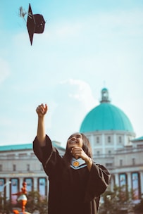 A joyful high school student holding a scholarship award certificate, standing in front of a school building.