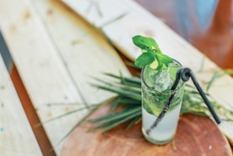 A vibrant glass of mojito garnished with fresh mint leaves and lime wedges on a rustic wooden table.