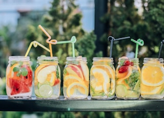 six clear glass mason jars filled with juice on black table