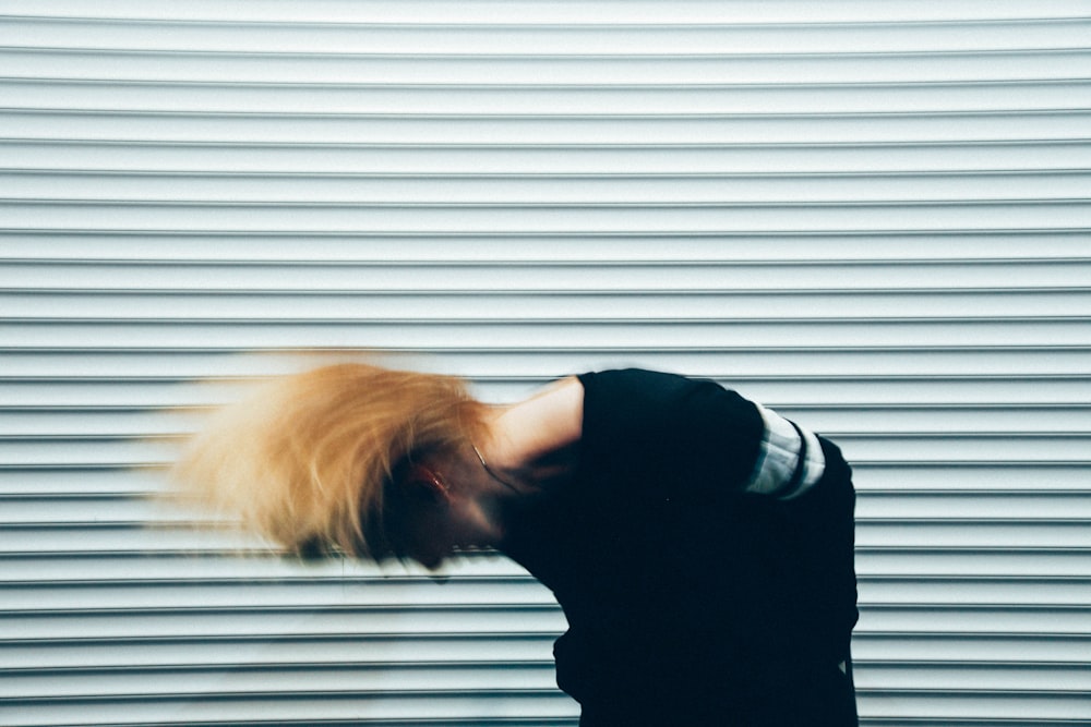 person wearing black and white shirt in front of grey wall