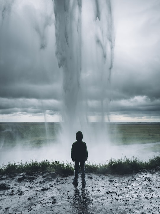toddler standing in front of water formation in Seljalandsfoss Iceland