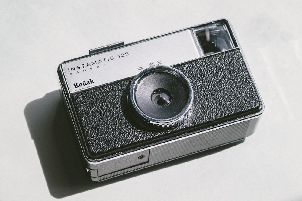 Fotocamera Kodak nera e grigia su superficie bianca