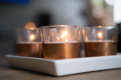 A set of tall, smooth pillar candles in warm cream tones arranged on a rustic wooden tray.