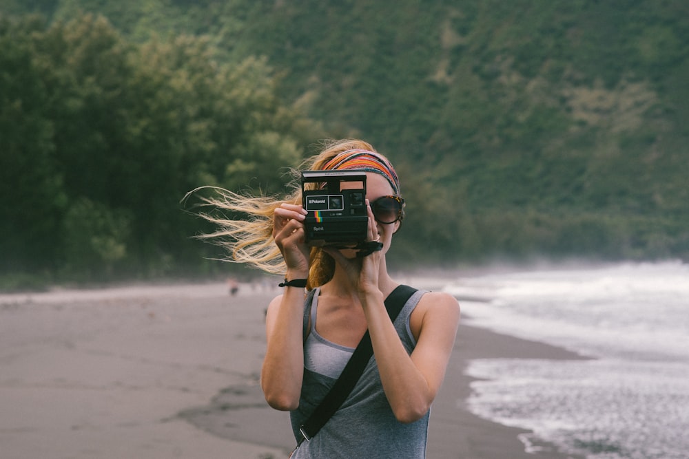 写真を撮る海岸の近くに立つ女性