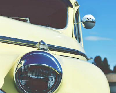Close-up of a technician carefully restoring a car headlight on a sunny day.