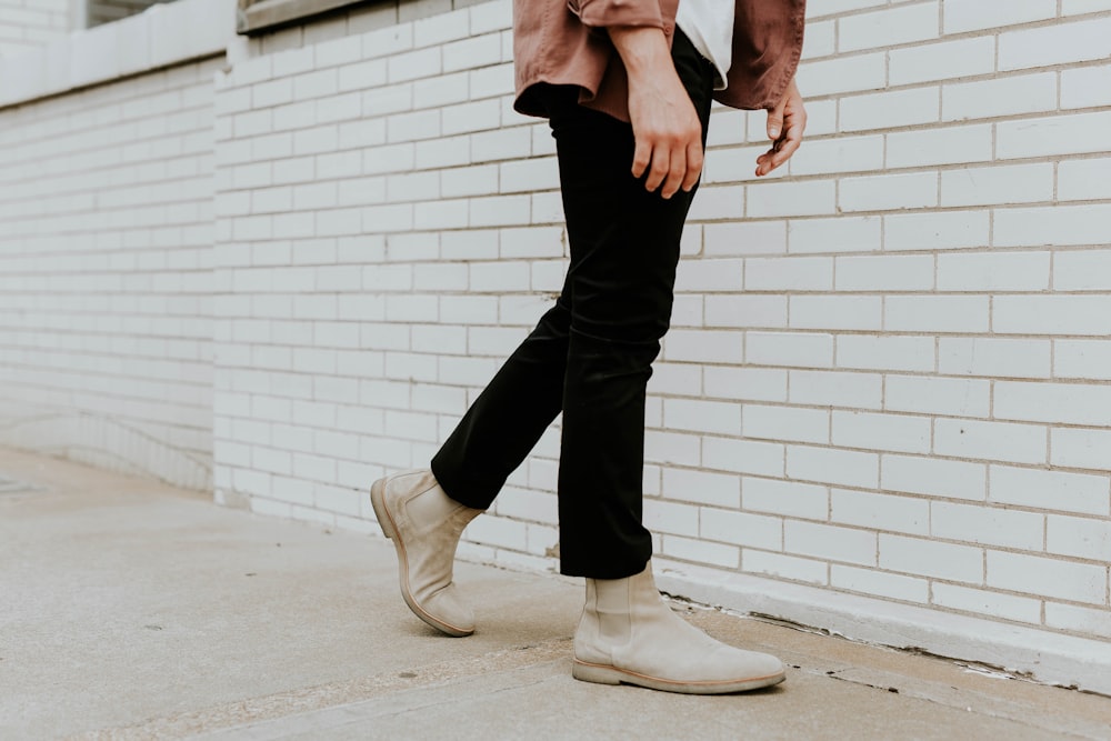 Persona con botines Chelsea de cuero blanco y pantalones negros