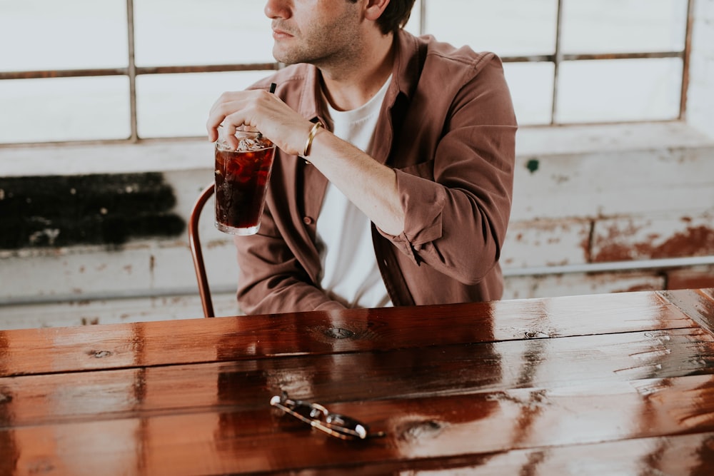 man holding drinking glass beside the table