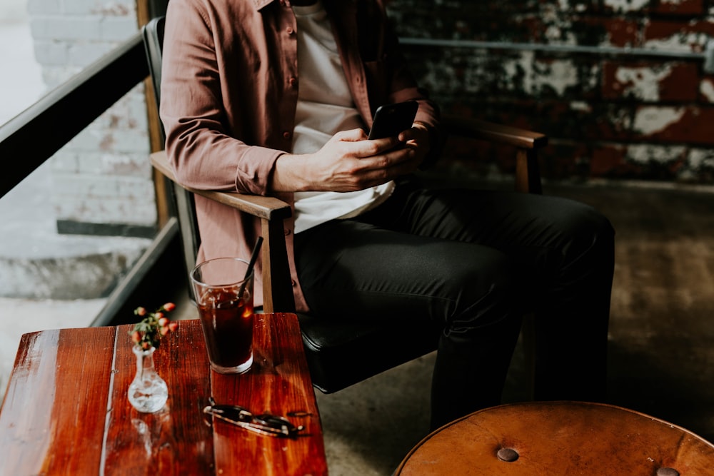 person using smartphone sitting on chair