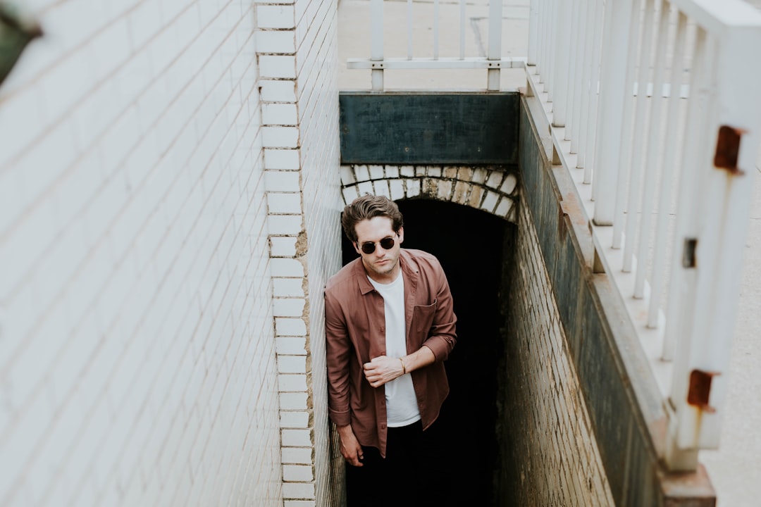 man leaning on wall while standing on stairs underground