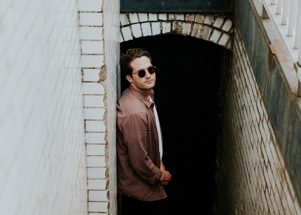 man leaning on beige wall near hallway