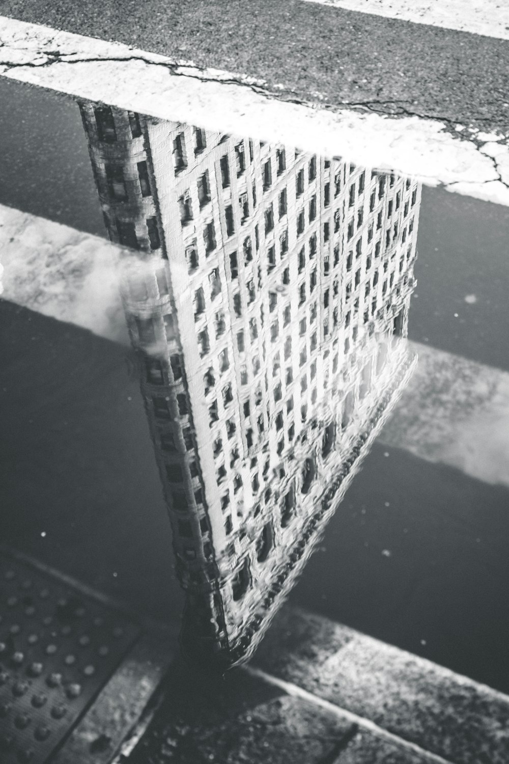 fotografia in scala di grigi del riflesso della costruzione sullo specchio d'acqua