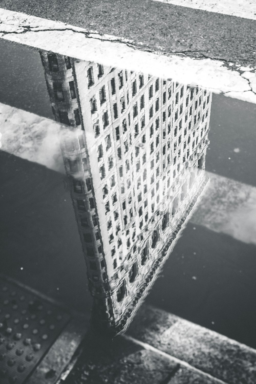 Photographie en niveaux de gris du reflet d’un bâtiment sur un plan d’eau