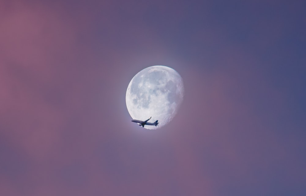 flying plane at sky during full moon at daytime