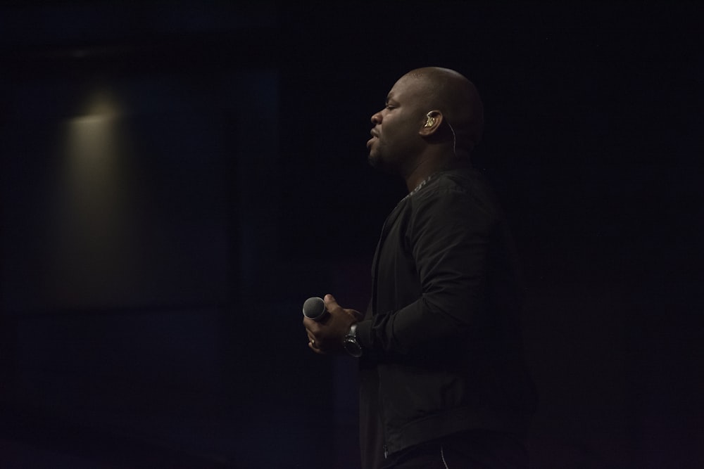 man holding microphone standing on stage