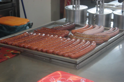 Assortment of pork sausages and ribs arranged on a butcher’s tray.