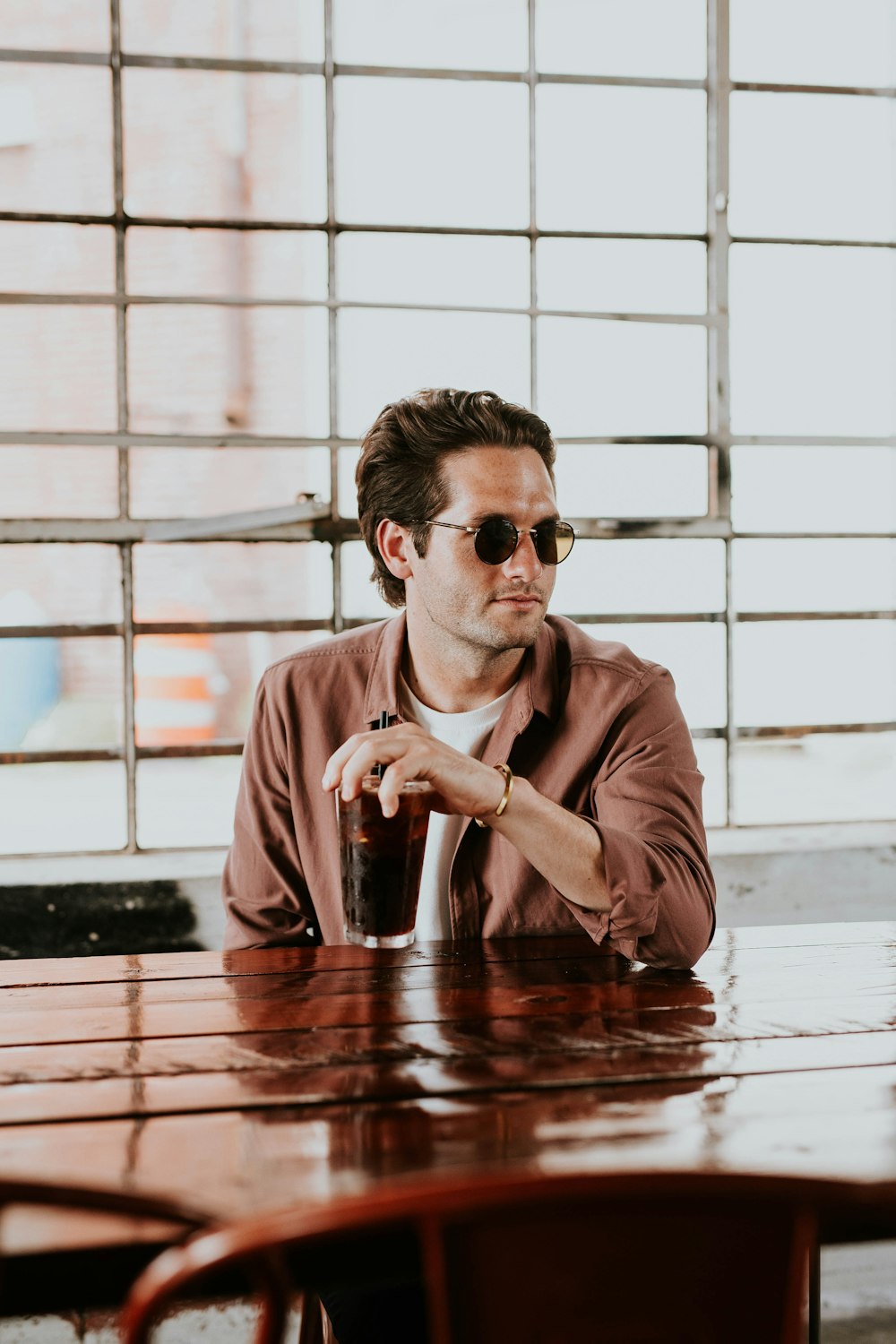 man wearing brown dress shirt holding drinking glass