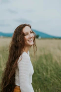 woman smiling white standing on green grass field during daytime