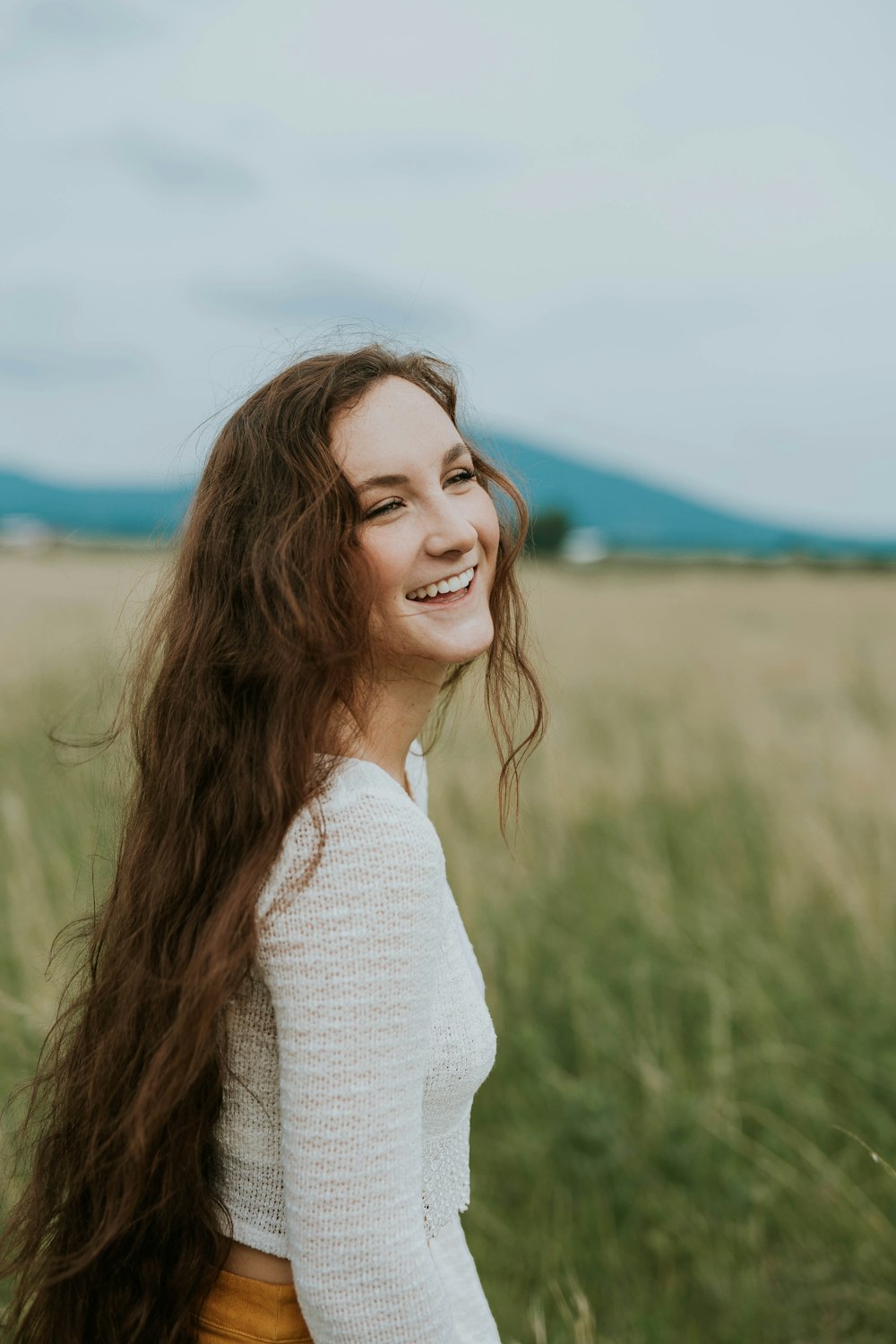 mulher sorrindo branco em pé no campo de grama verde durante o dia