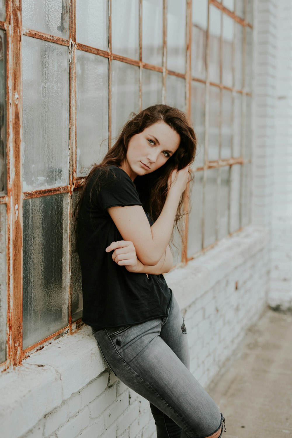 woman and black crew-neck T-shirt lying beside glass window