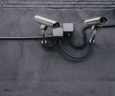 two bullet surveillance cameras attached on wall