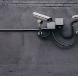 two bullet surveillance cameras attached on wall