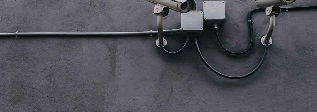 two bullet surveillance cameras attached on wall