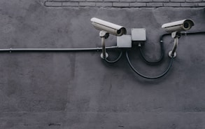 two bullet surveillance cameras attached on wall