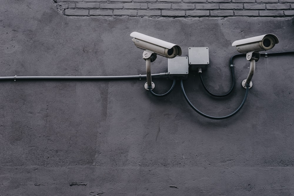 Two CCTV cameras on a gray wall