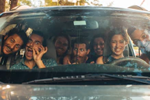 A car filled with happy students on a road trip.