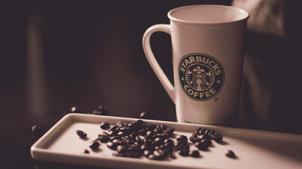 coffee beans beside Starbucks coffee mug