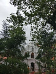Elegant chapel entrance framed by delicate pastel flowers and soft gold detailing under a clear sky.