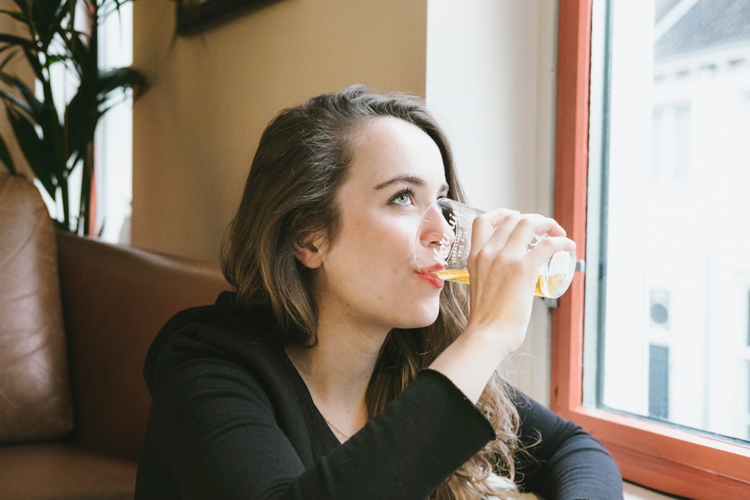 woman sipping beverage on drinking glasses indoors
