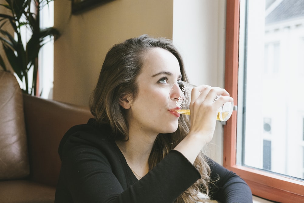 woman sipping beverage on drinking glasses indoors