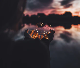 person holding turned on string lights during nighttime