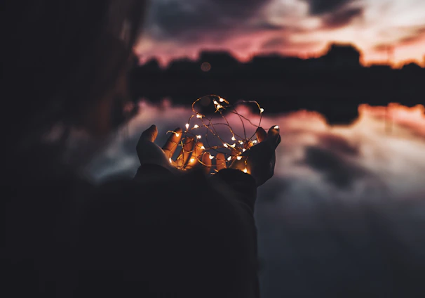 person holding turned on string lights during nighttime