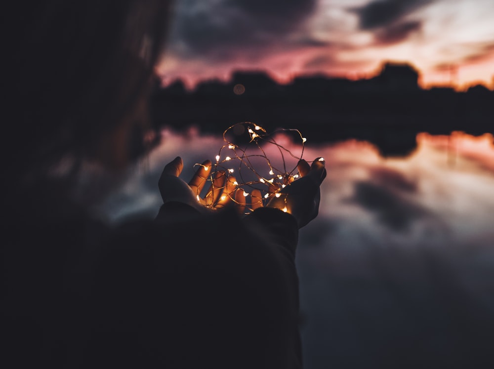 person holding turned on string lights during nighttime