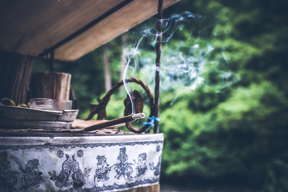 A burning incense stick on a wooden surface outdoors