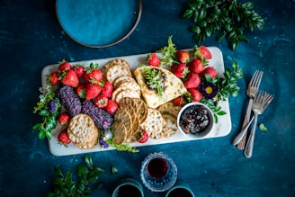 a platter of crackers, strawberries, and fruit