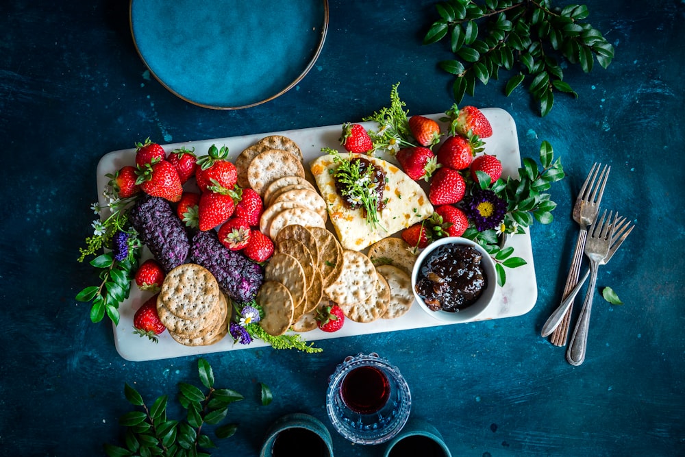 a platter of crackers, strawberries, and fruit