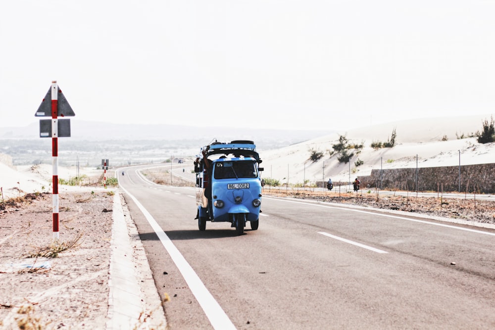 blue auto-rickshaw beside road signage