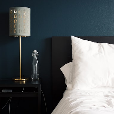 gray table lamp beside white bed pillow