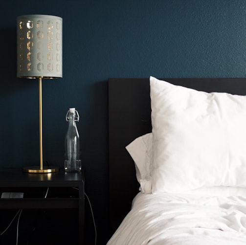 gray table lamp beside white bed pillow