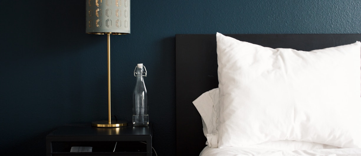 gray table lamp beside white bed pillow