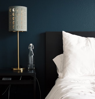 gray table lamp beside white bed pillow